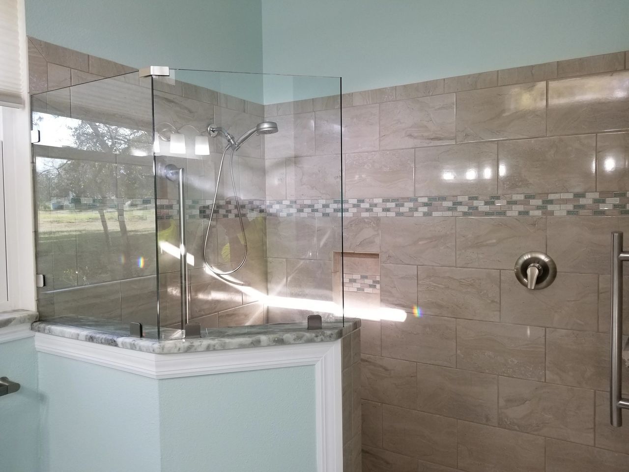 A bathroom with a walk in shower with a glass door.