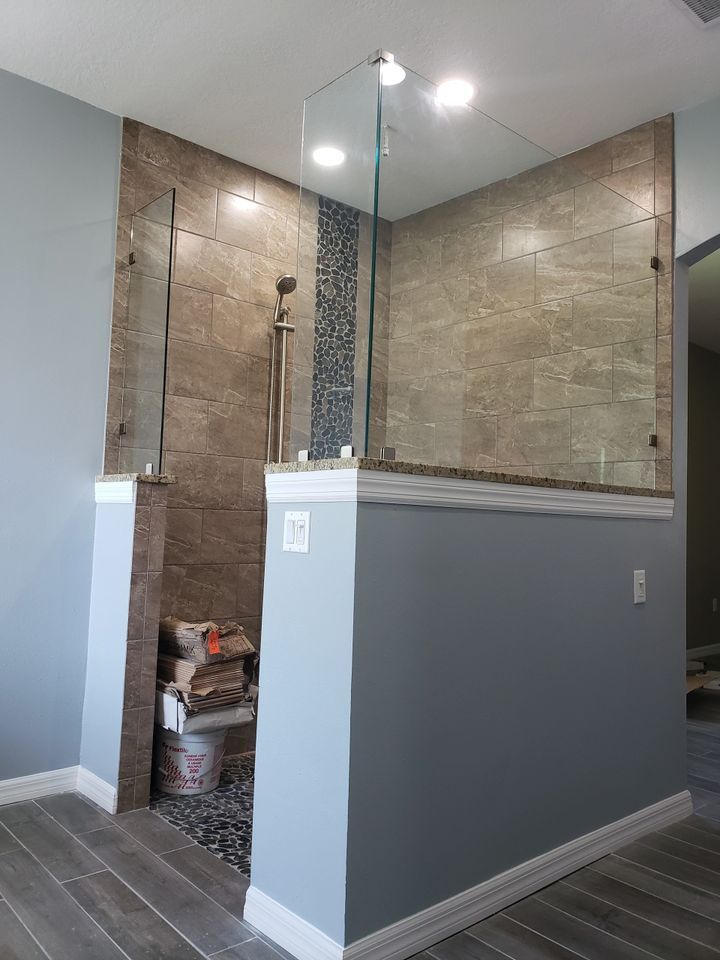 A bathroom with a walk in shower with a glass door.