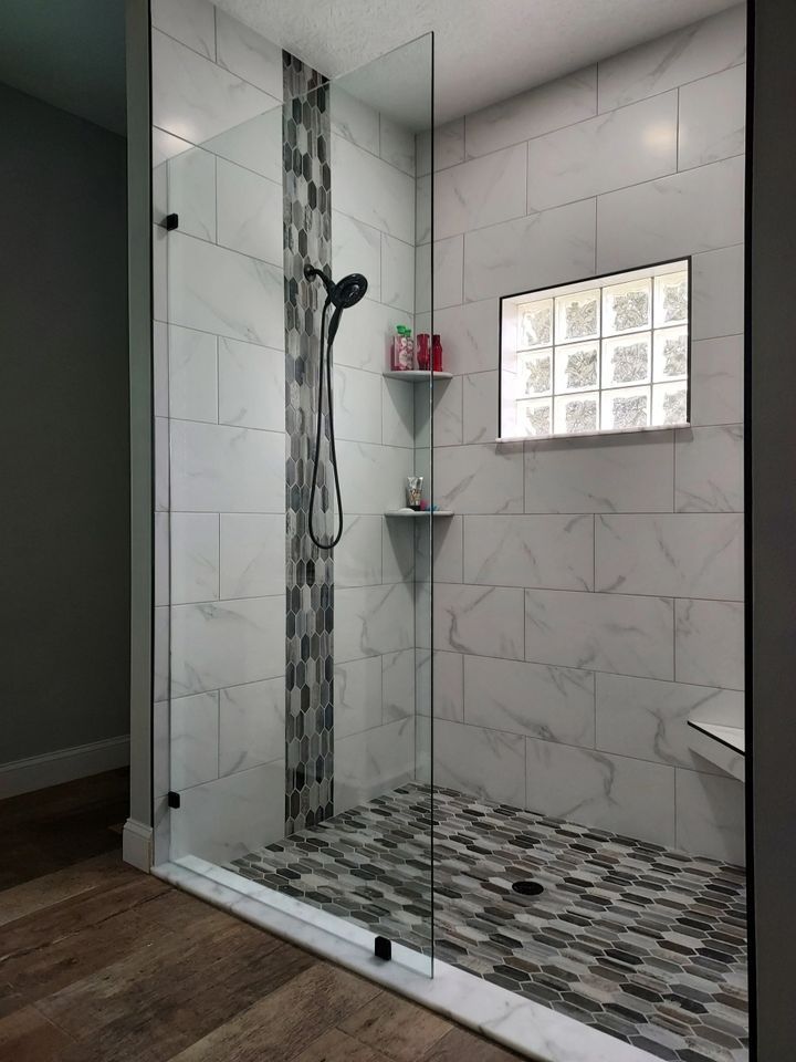 A walk in shower with a glass door and a shower head.