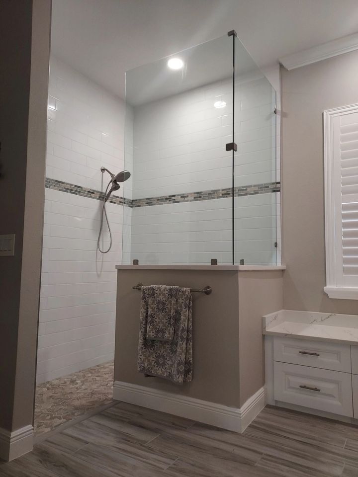 A bathroom with a walk in shower and a window.