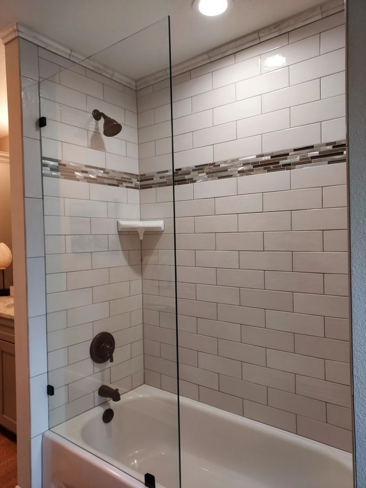 A bathtub in a bathroom with a glass shower door