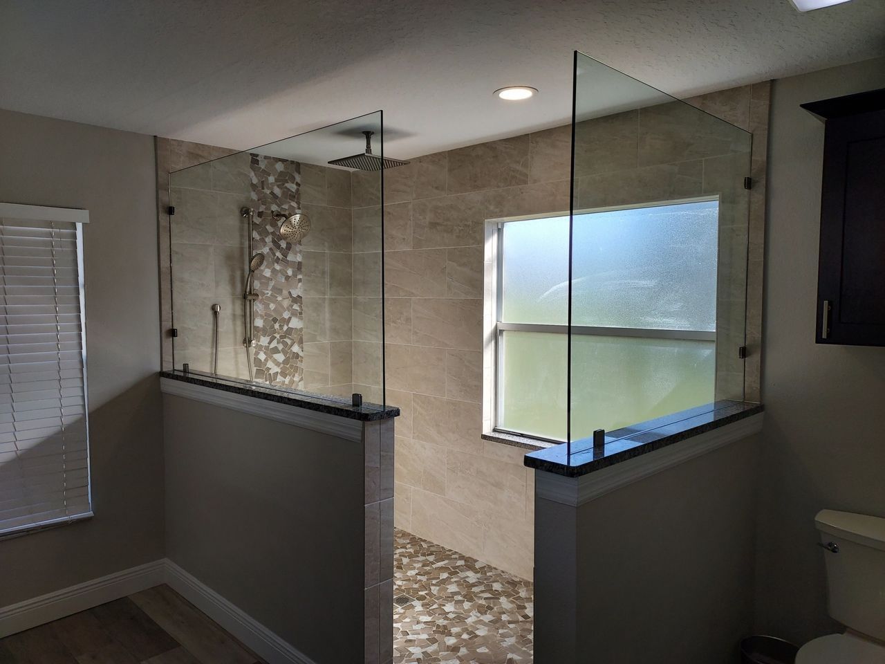 A bathroom with a walk in shower and a window.