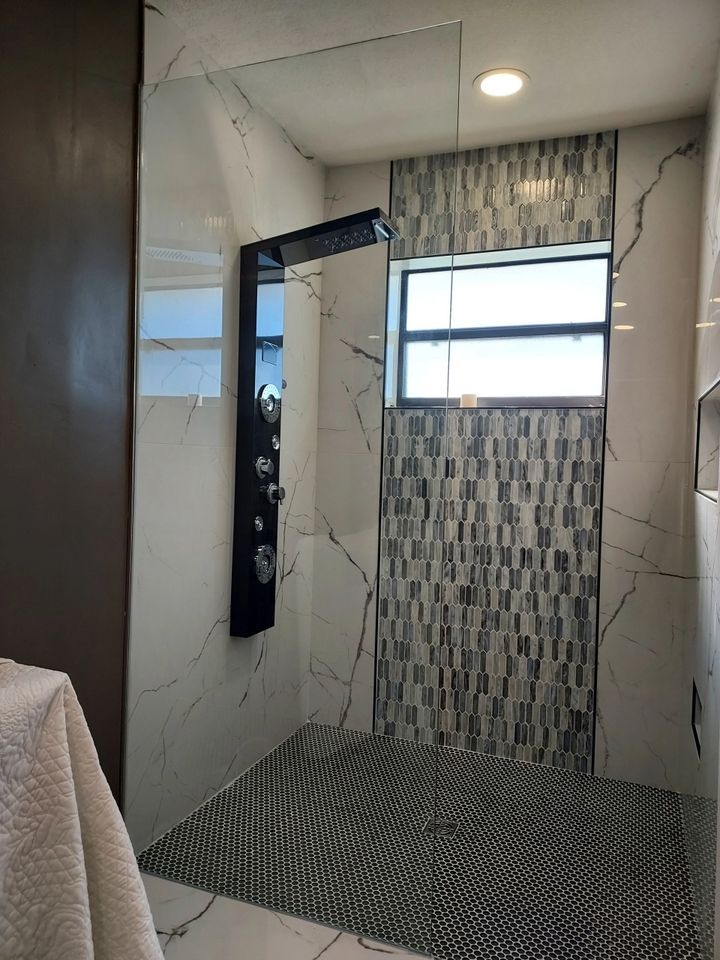 A bathroom with a walk in shower and a window.