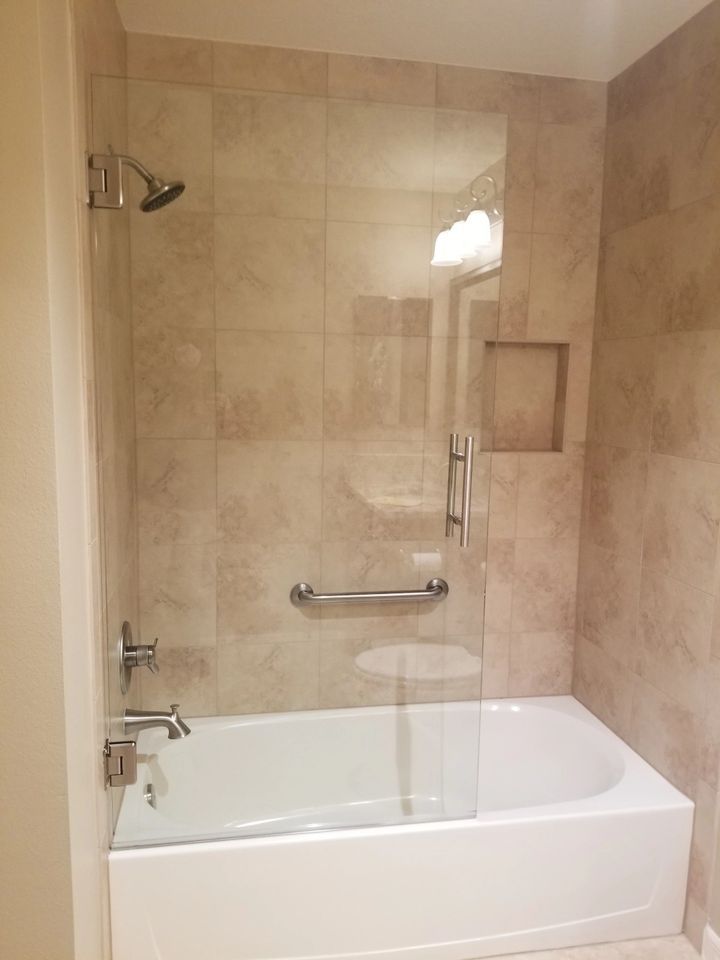 A bathroom with a bathtub and a shower with a glass door.