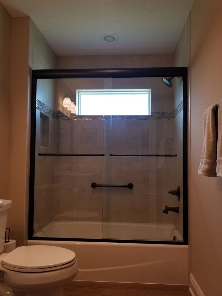 A bathroom with a toilet , tub , shower and window.
