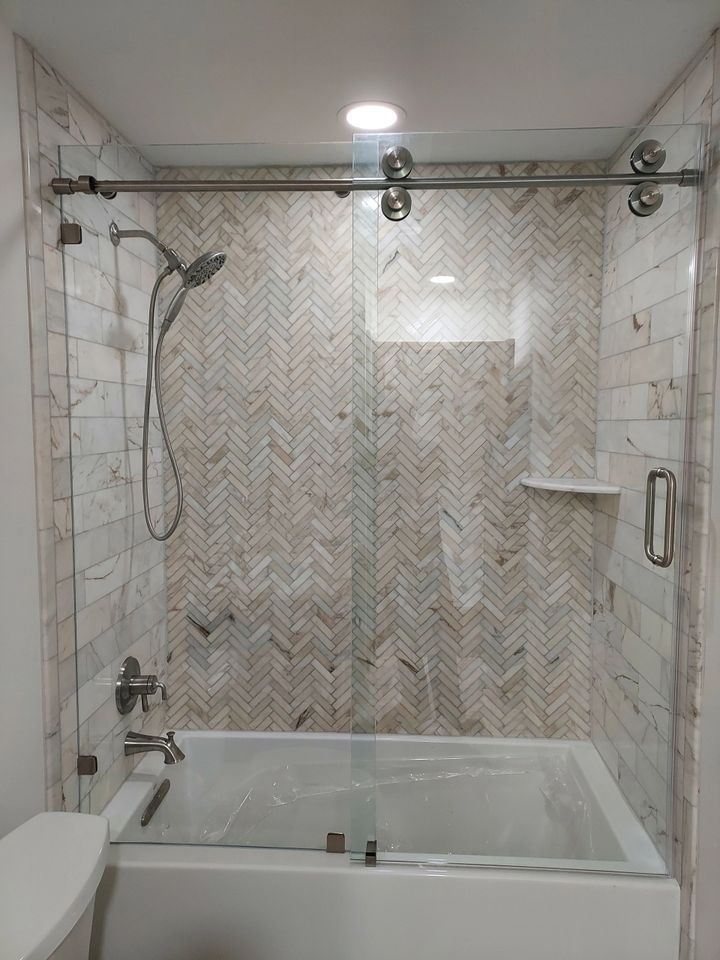 A bathroom with a bathtub , toilet , shower and sliding glass door.