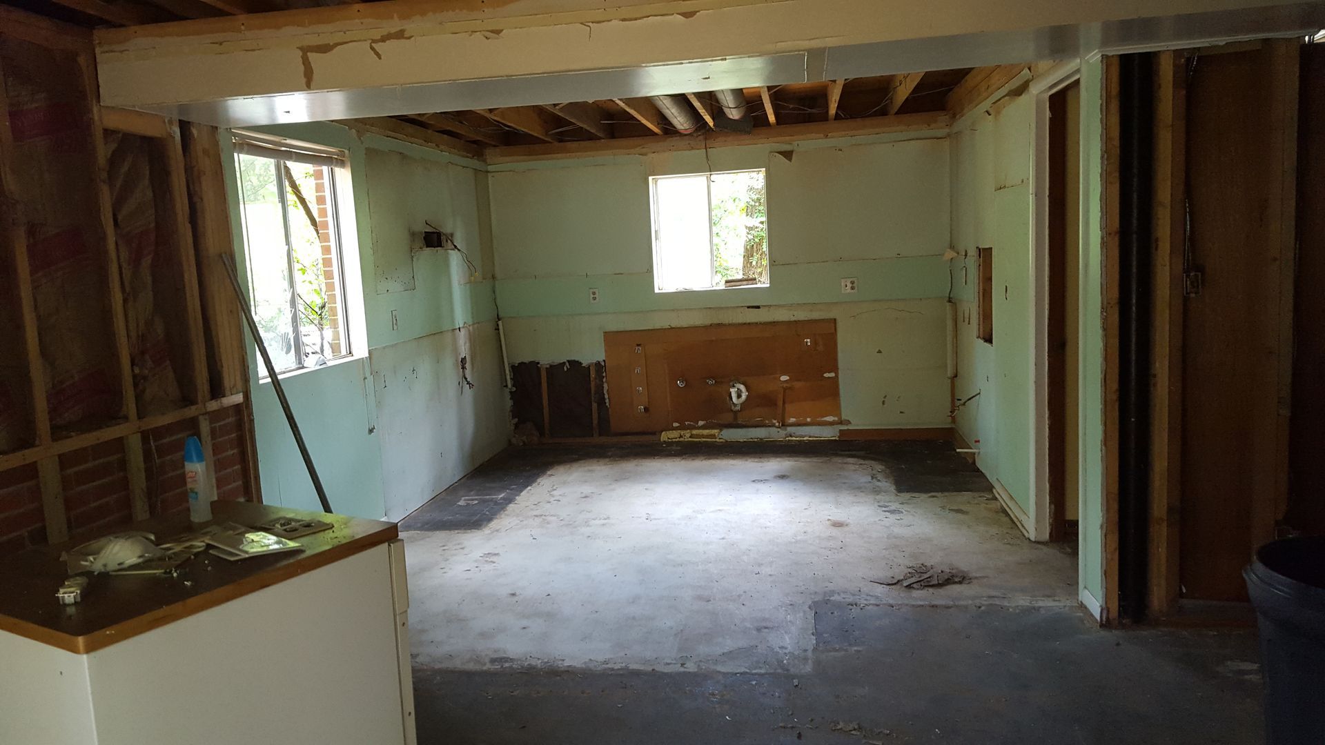An unfinished interior room with bare walls, exposed wooden studs, a concrete floor, and an open doorway.