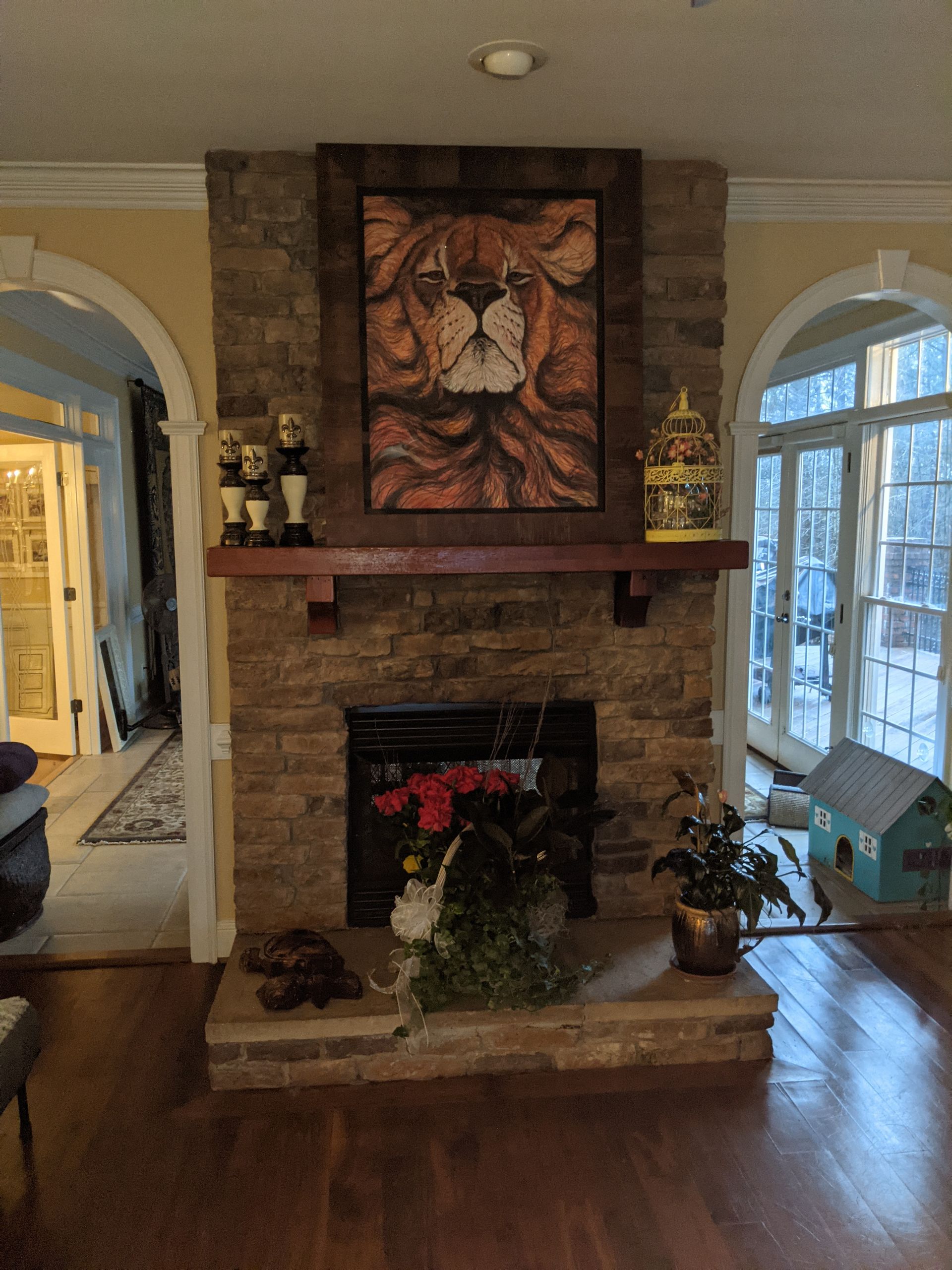 A stone fireplace features a prominent framed lion portrait above the mantel, flanked by decorative items and greenery.