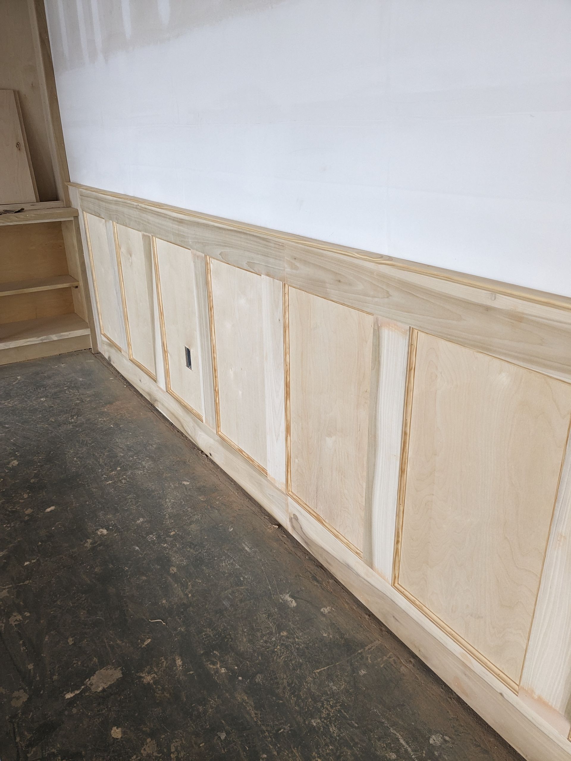 Wooden wainscoting with decorative rope molding installed on a wall in a room under renovation.
