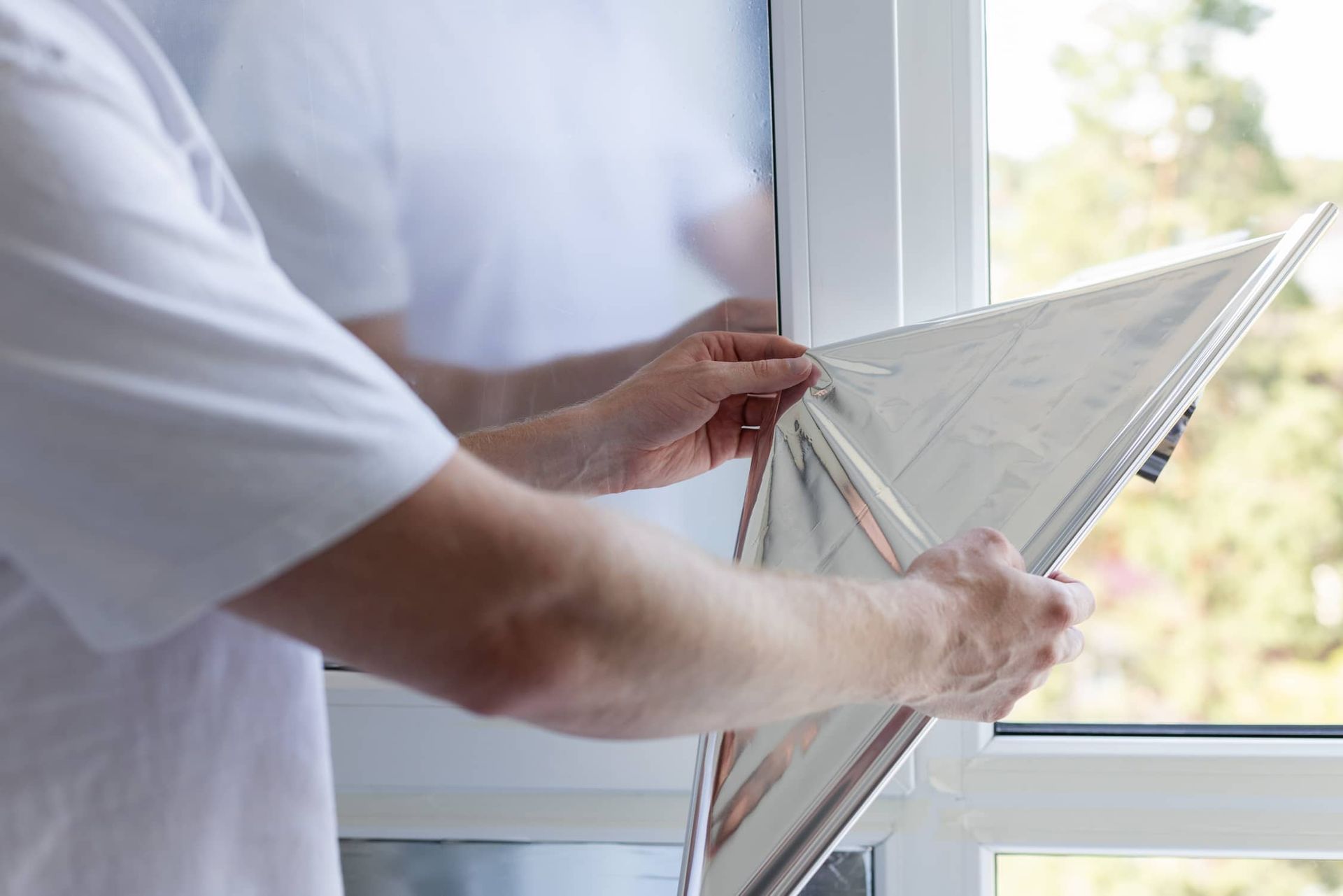 a Man is Holding a Piece of Paper in Front of a Window — Total Tint Bendigo in East Bendigo, VIC