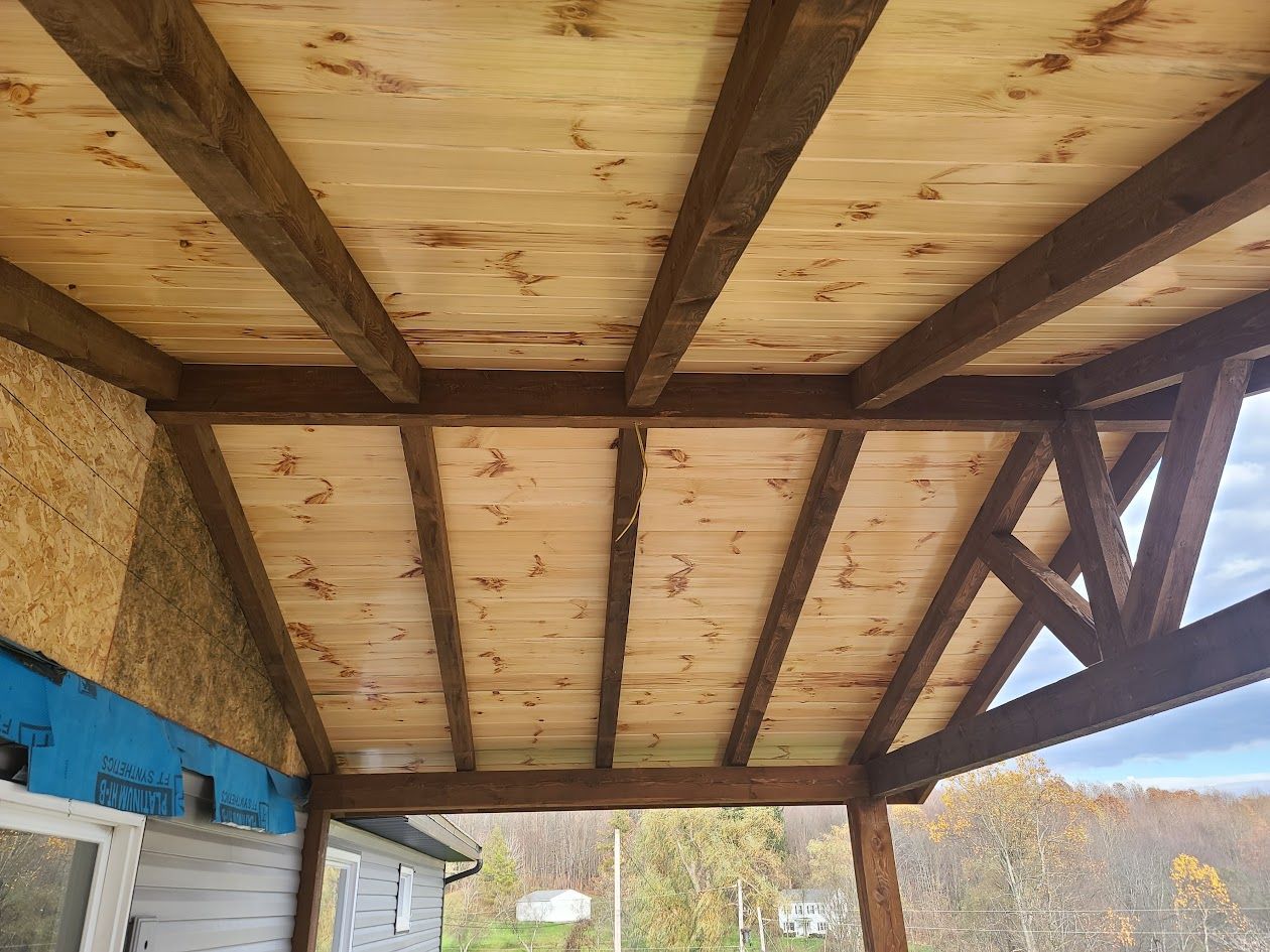 A wooden porch with a wooden ceiling and beams.