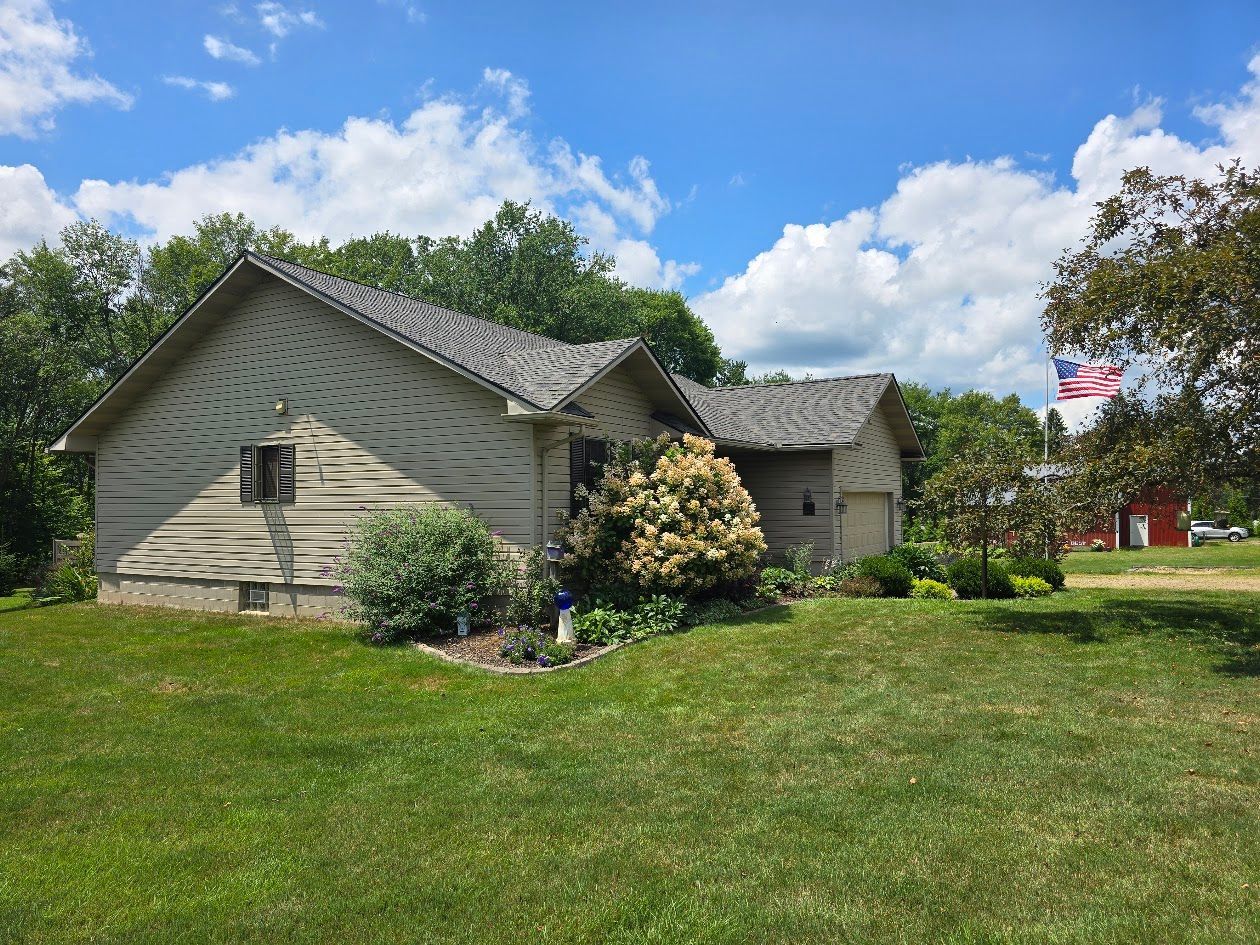 A house with a large lawn in front of it and a flag in the background.