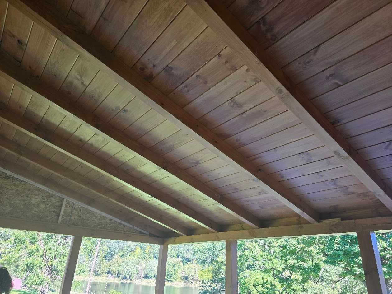 A wooden ceiling with a view of trees in the background