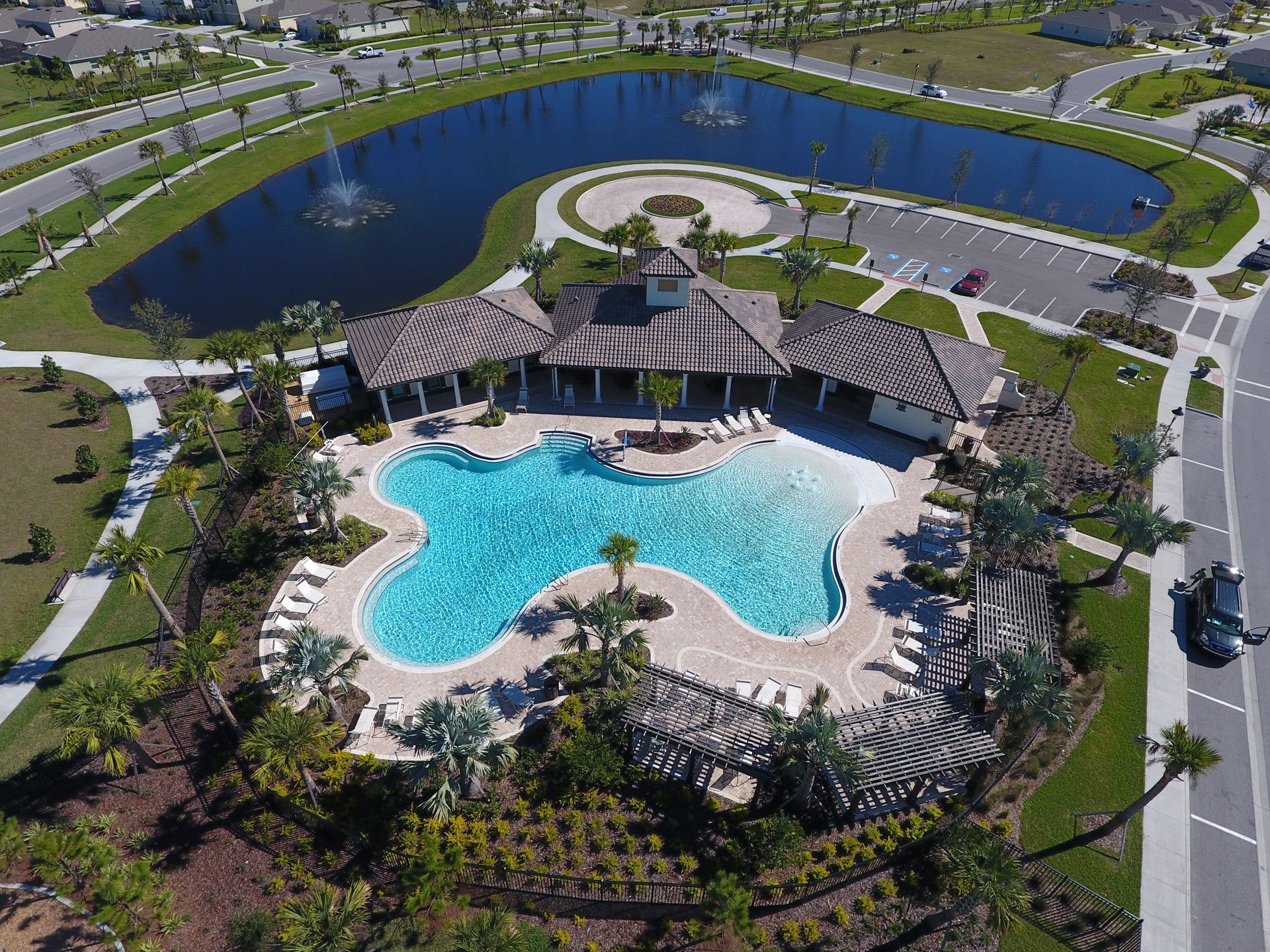 An aerial view of a large swimming pool surrounded by trees and a lake.