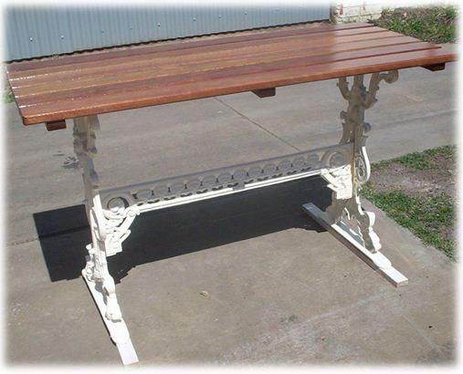 A wooden table with a white base sits on a sidewalk