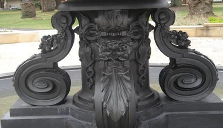 A black statue with swirls and a face on it