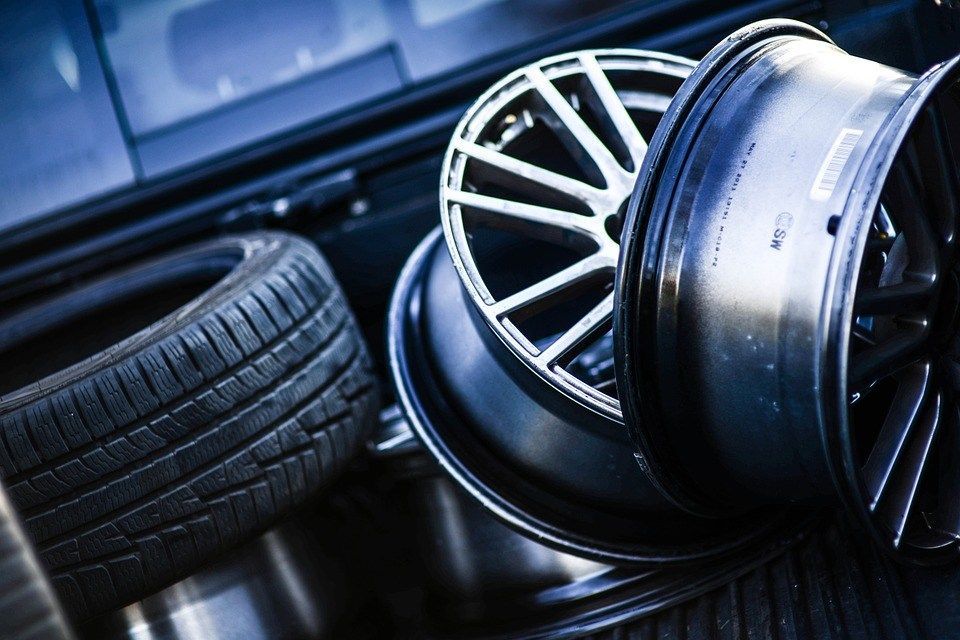 Tires and alloy wheels stacked, close up. The rims are silver and black, the tires are black.