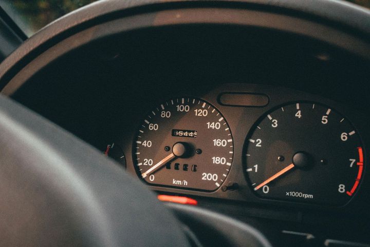Car dashboard with speedometer and tachometer gauges lit up.