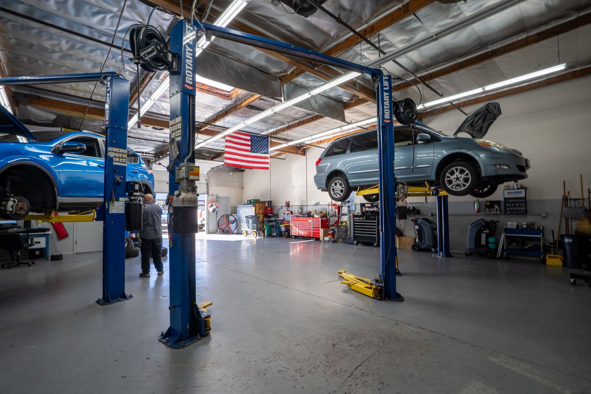Mechanic working on a car engine, using tools under the hood.