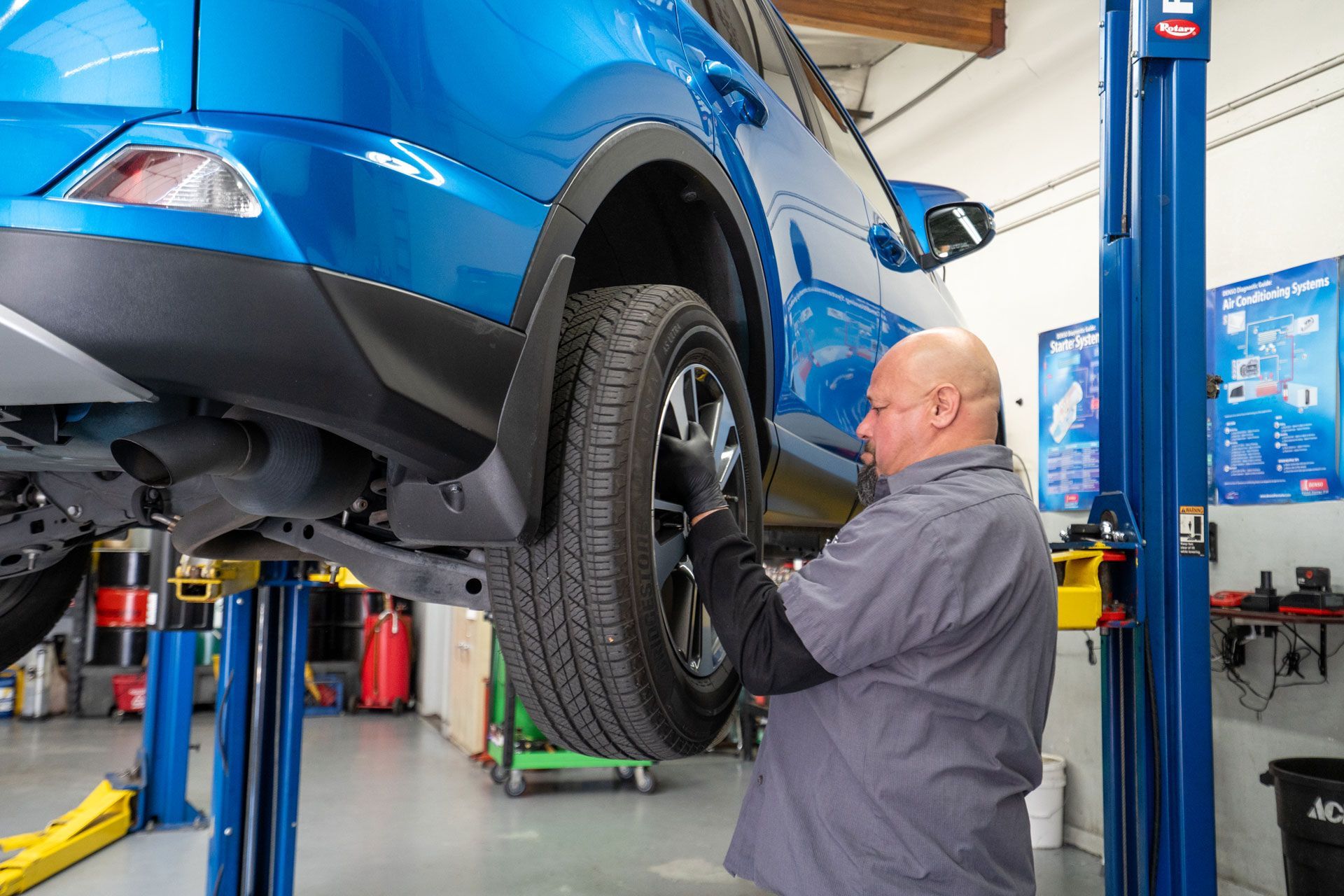 Mechanic adjusting wheel alignment on a car in a shop.