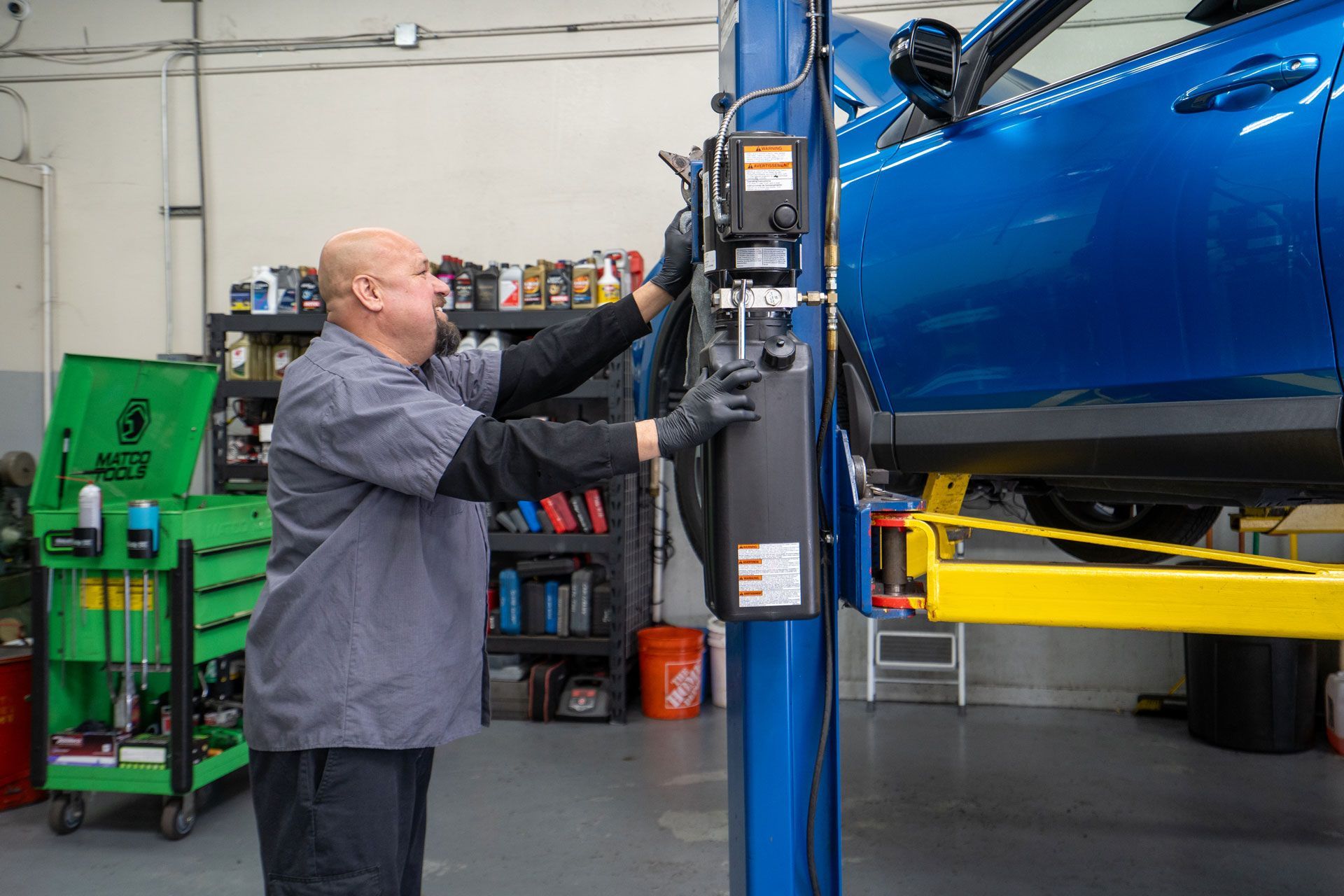 Auto repair shop with three cars on lifts, tools, and a worker.