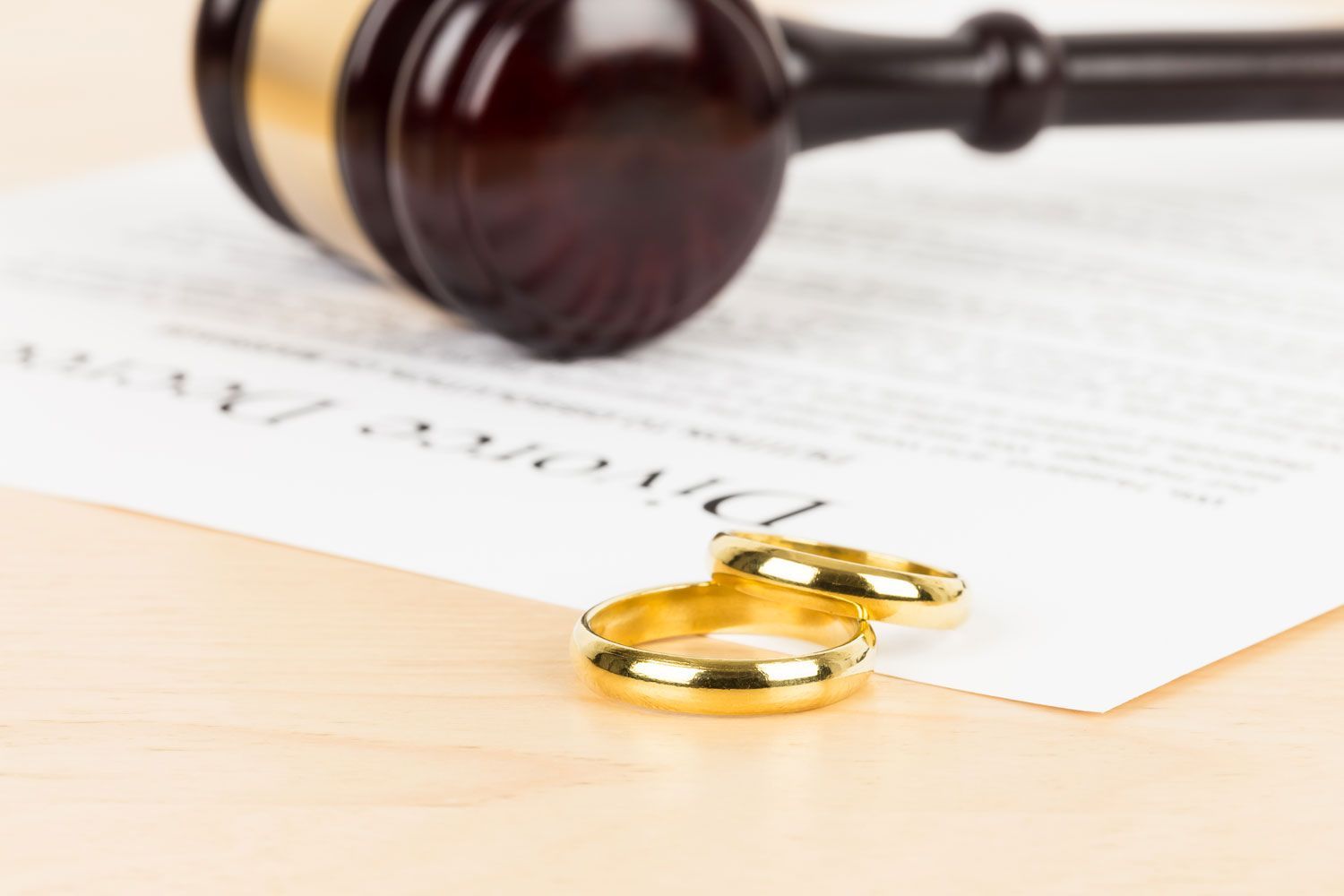 wooden judge gavel, golden rings, and divorce decree