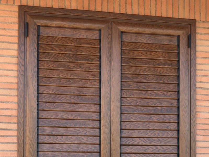 Una finestra con persiane di legno su un muro di mattoni.