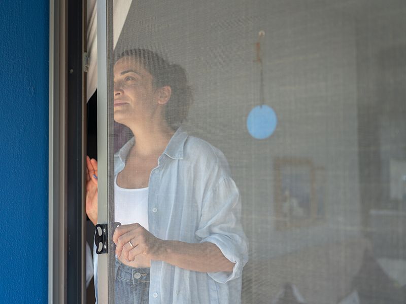 Una donna è in piedi davanti a una porta a soffietto e guarda fuori dalla finestra.