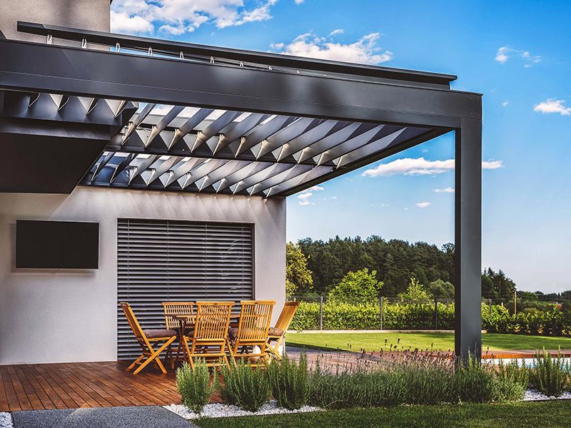 Un patio con tavolo e sedie sotto un pergolato.