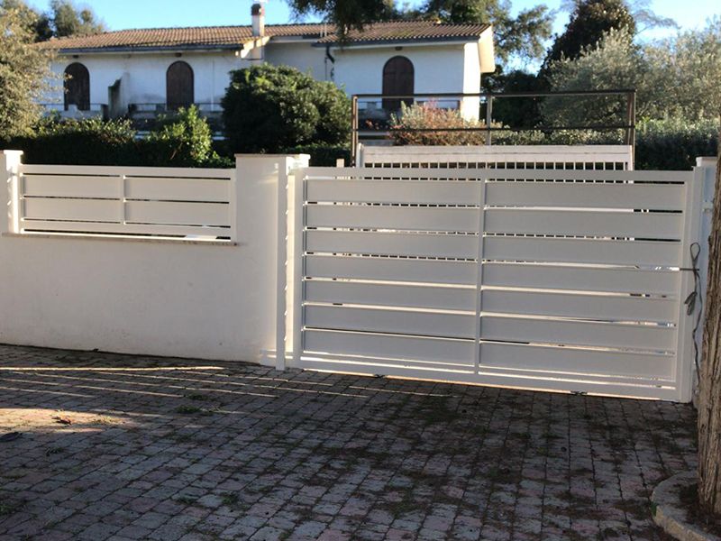 Un cancello bianco è aperto davanti a una casa bianca