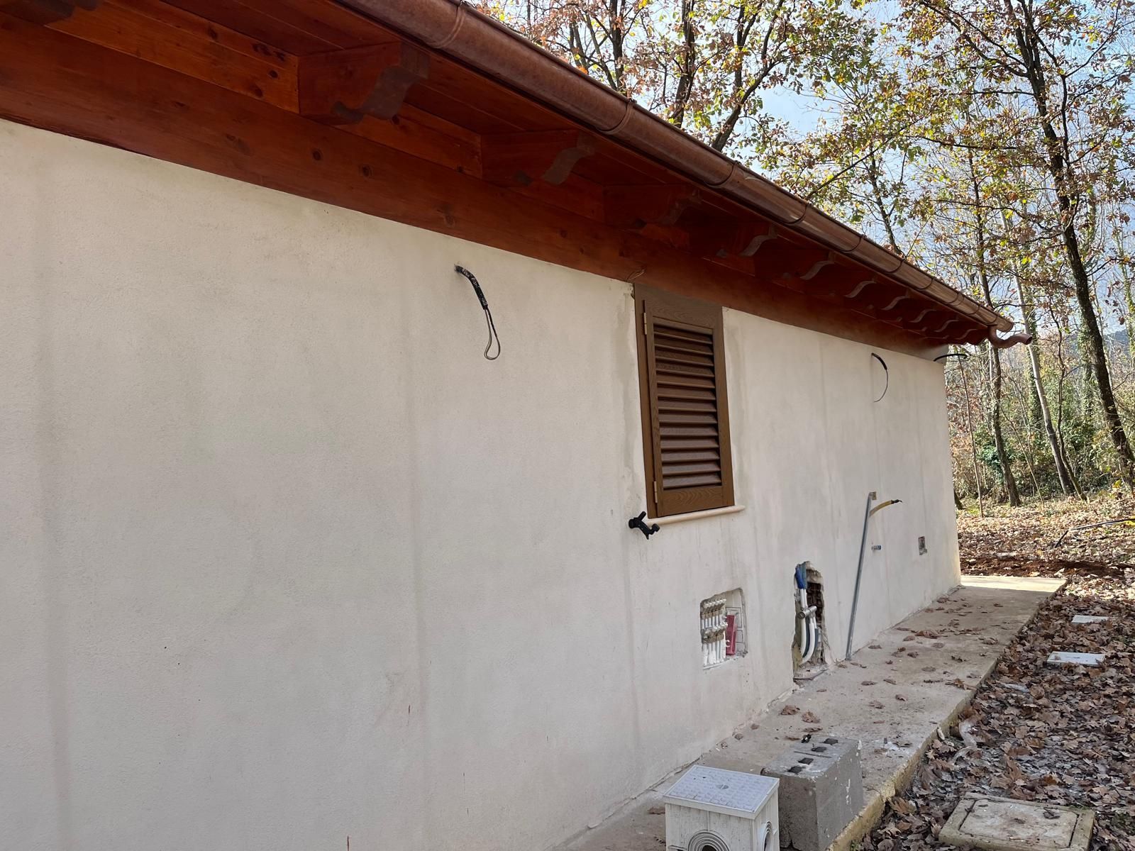 Un edificio bianco con un tetto di legno e una finestra.