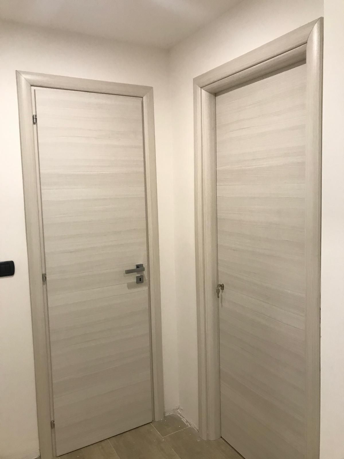 Due porte bianche sono una accanto all'altra in un corridoio.