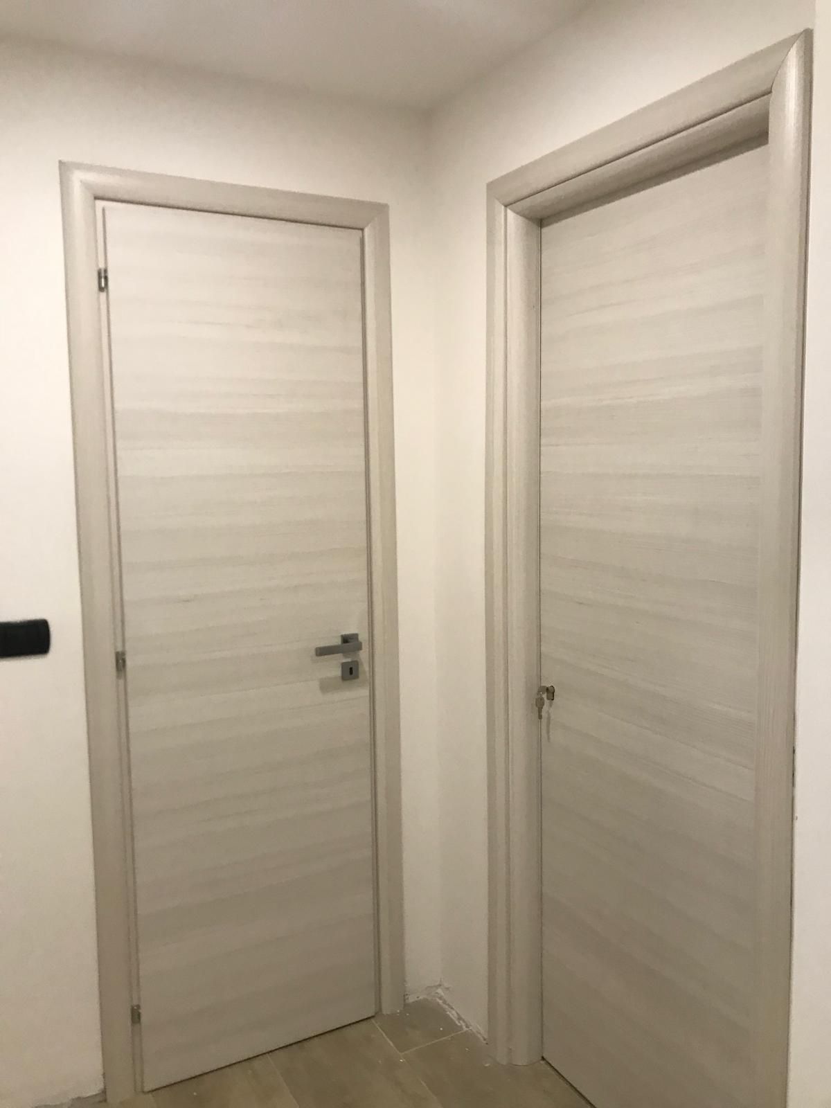 Due porte bianche sono una accanto all'altra in un corridoio.