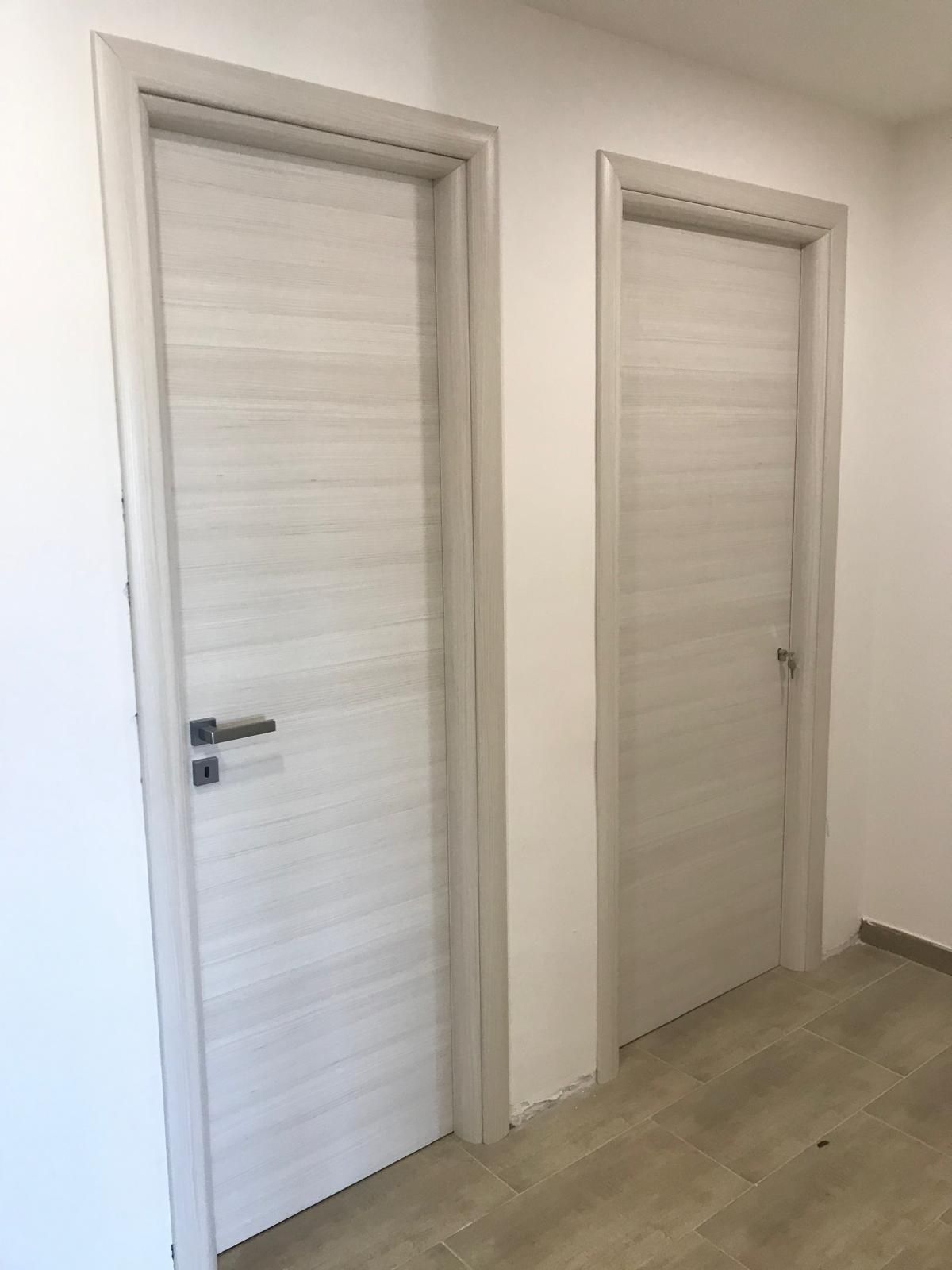 Due porte bianche sono una accanto all'altra in un corridoio.