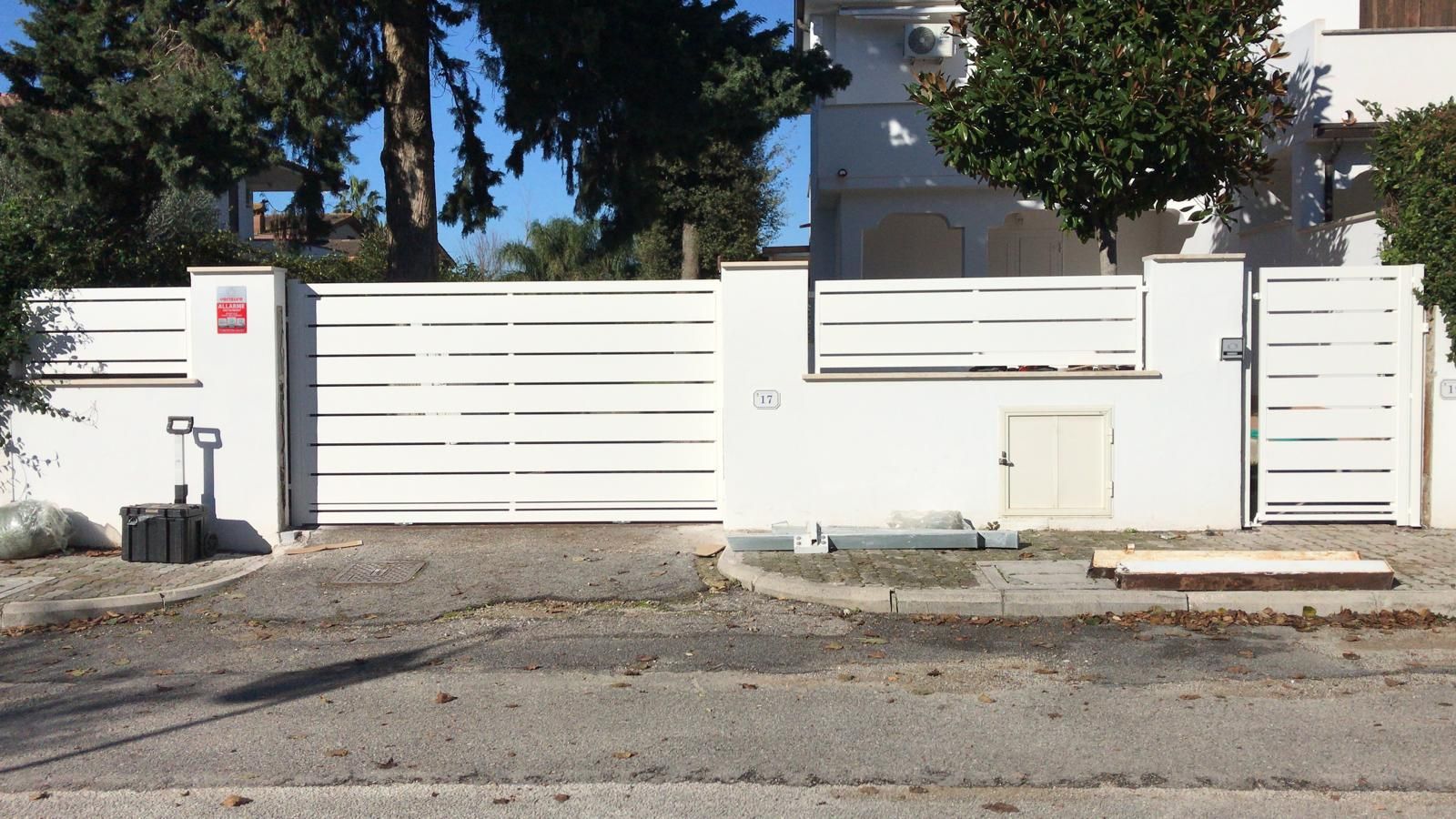 Una recinzione bianca con un cancello scorrevole davanti a una casa