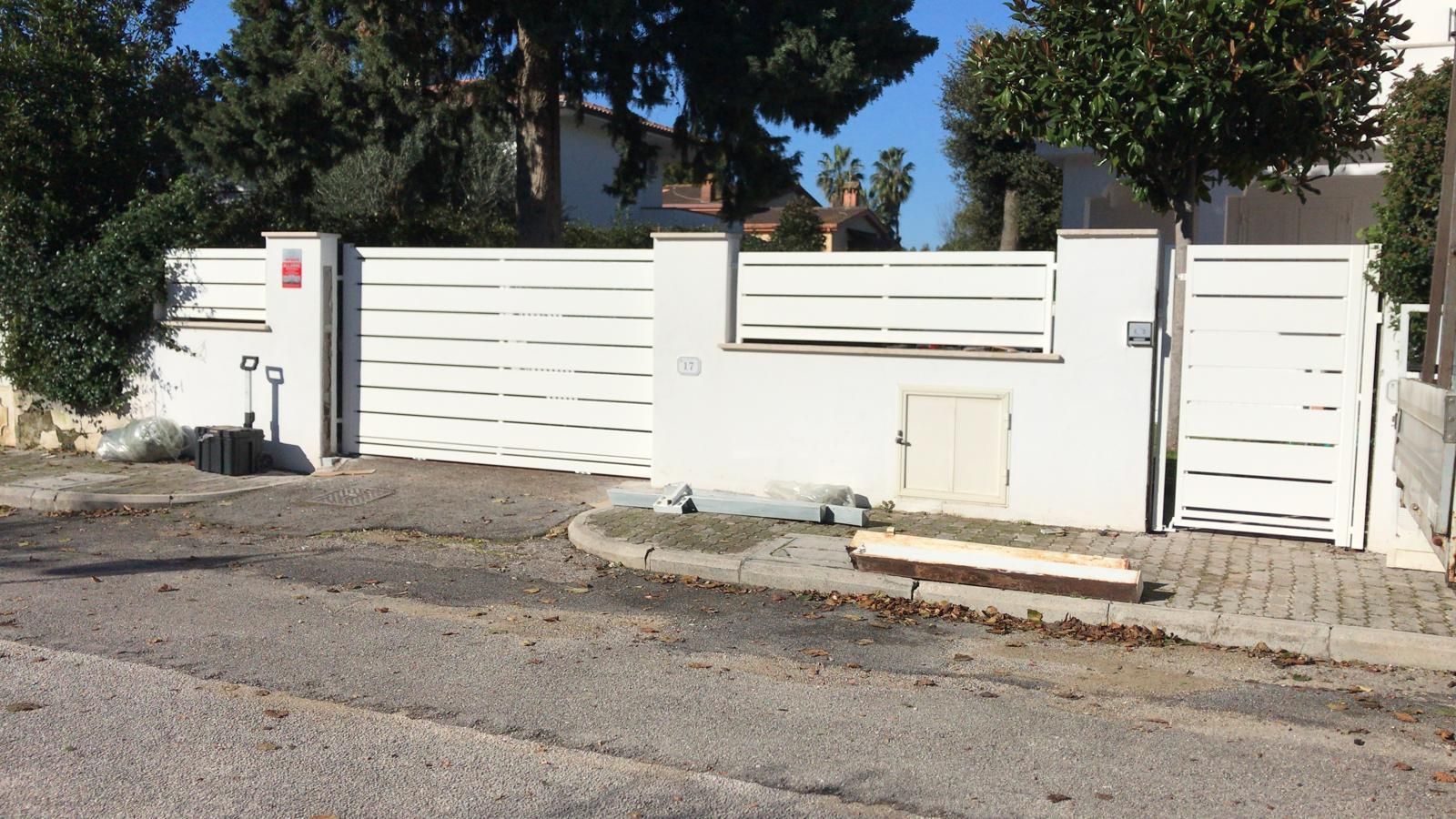 Una recinzione bianca circonda una casa sul ciglio della strada.