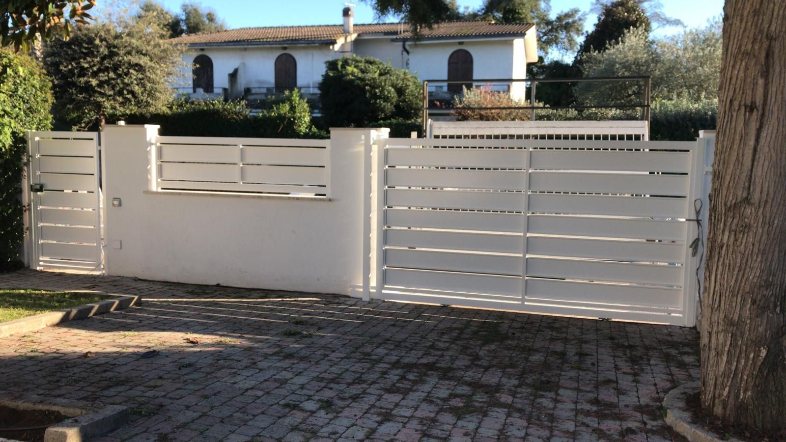 Una recinzione bianca circonda il vialetto di accesso di fronte a una casa.