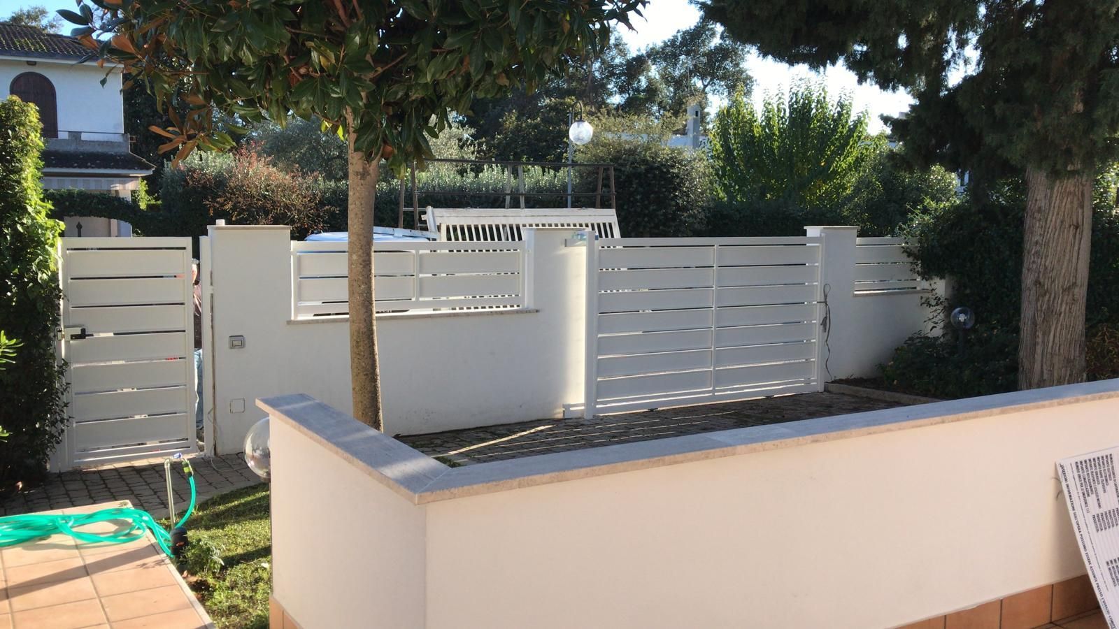 Una recinzione bianca con un cancello e alberi sullo sfondo