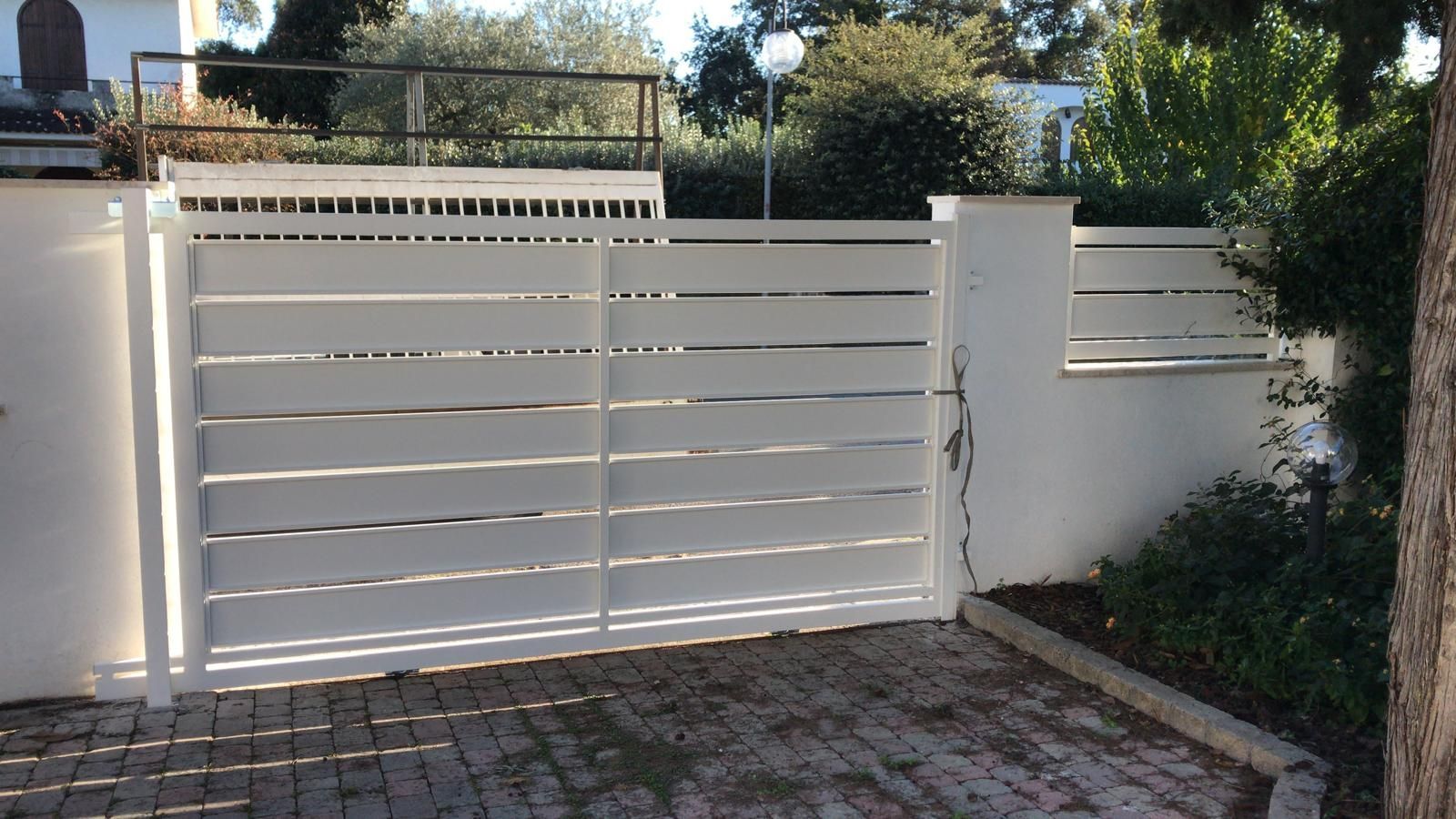 Un cancello bianco è aperto davanti a una casa