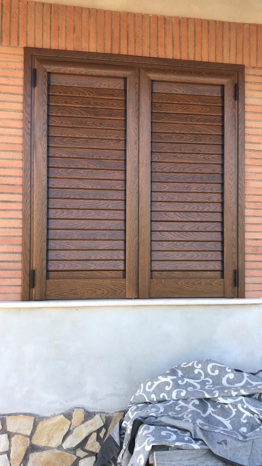 Una finestra con persiane di legno su un muro di mattoni.