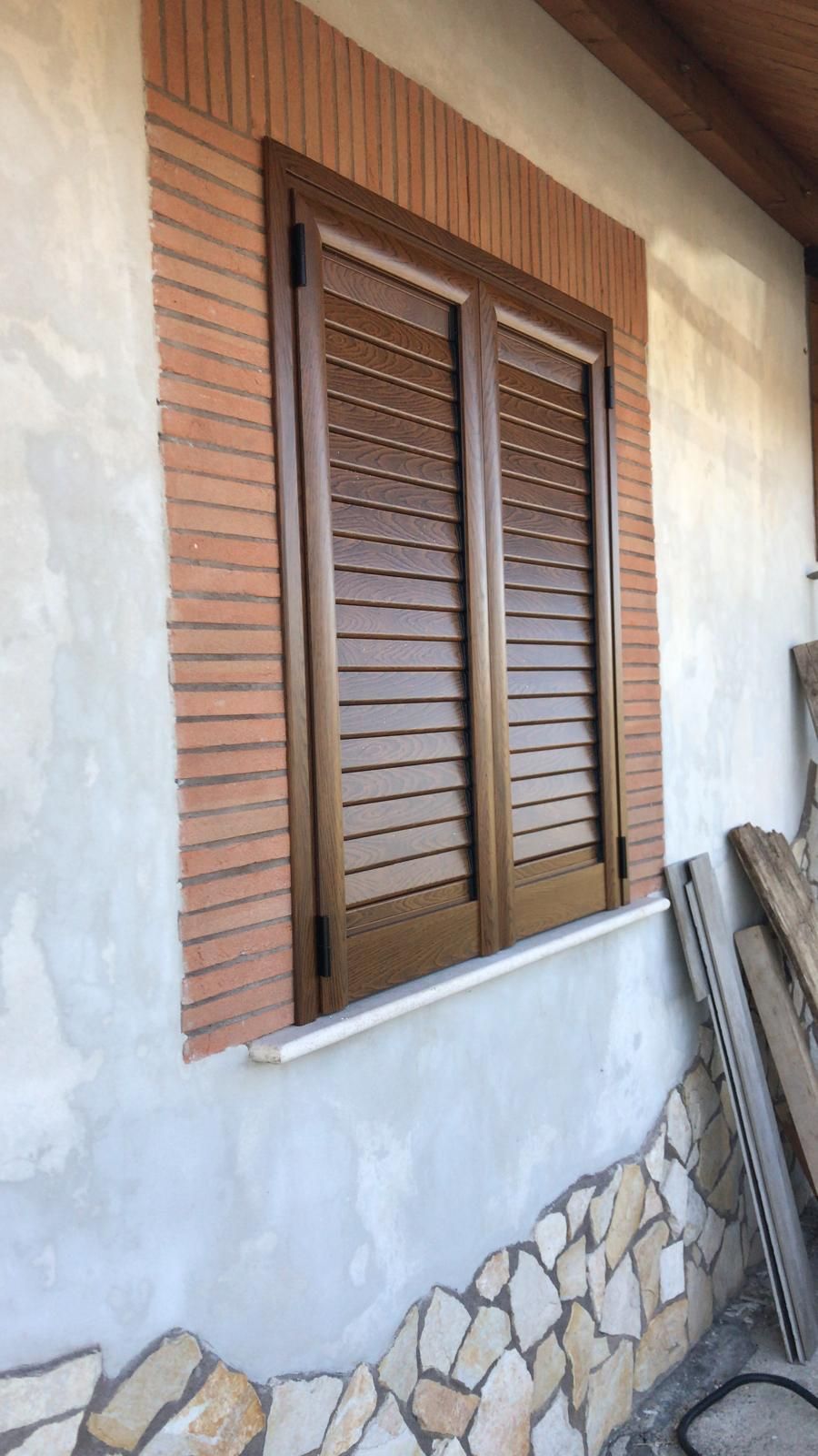 Una finestra con persiane di legno su un muro di mattoni.