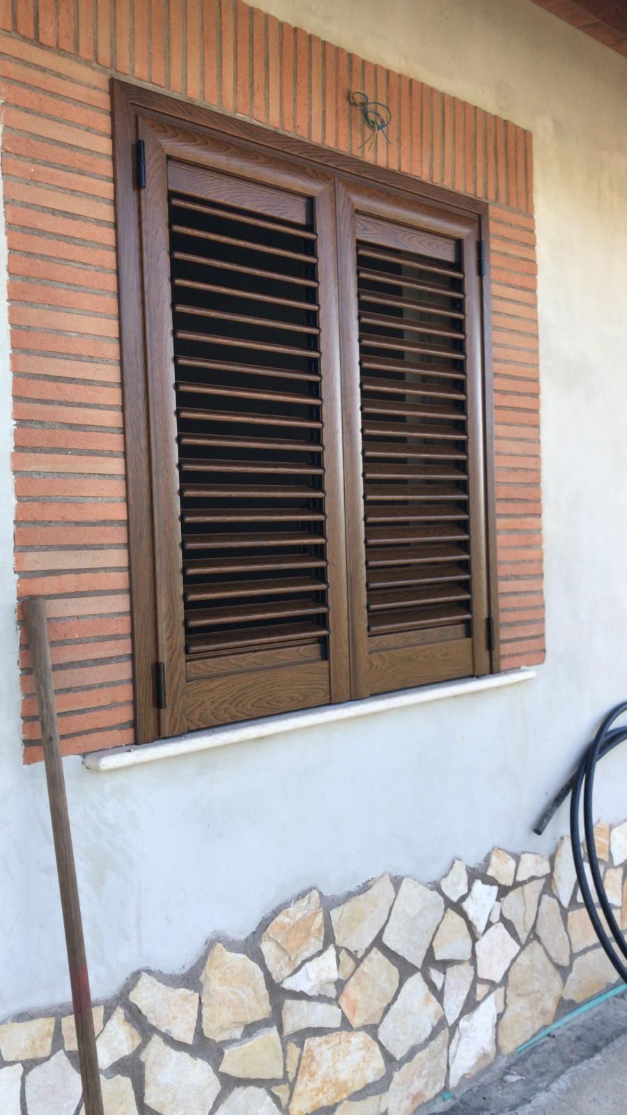 Una finestra con persiane di legno su un muro di mattoni.