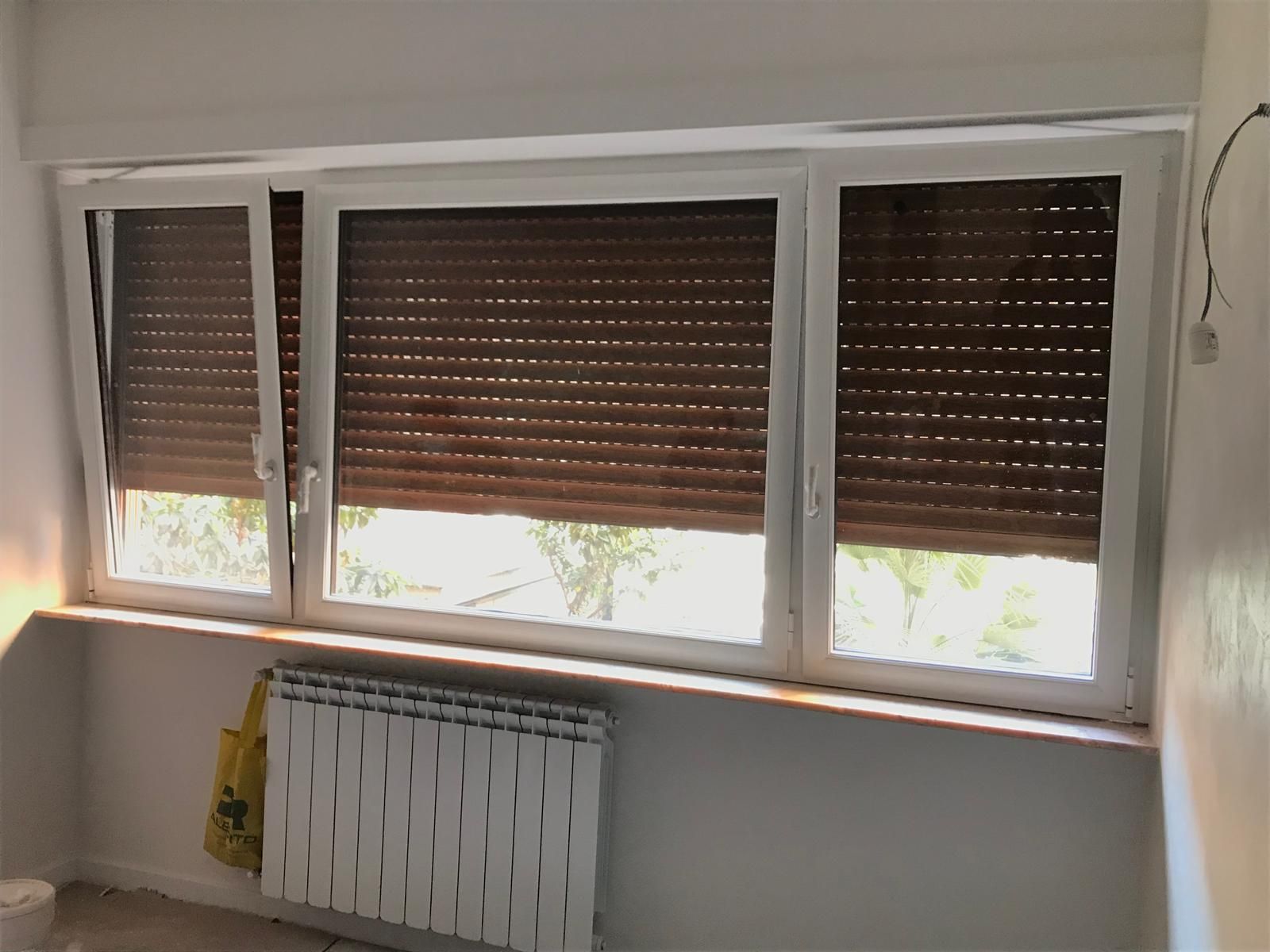 Una stanza con un termosifone e una finestra con le persiane