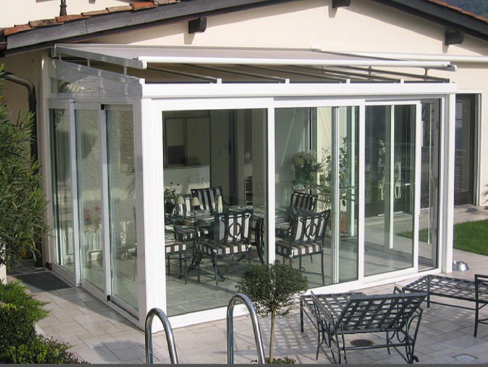 Una casa con una grande stanza vetrata con tavoli e sedie