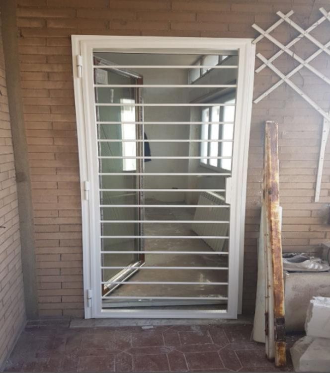 Un muro di mattoni con una porta bianca con le sbarre