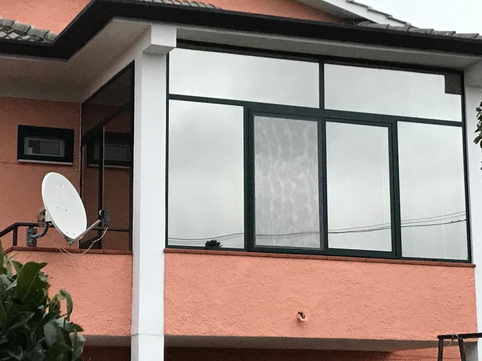 Una casa con una grande finestra e una parabola satellitare sul balcone.