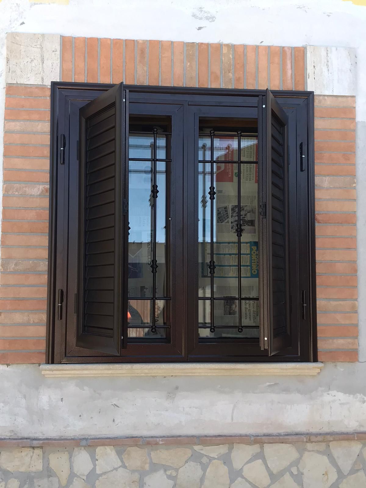 Una finestra con le persiane è su un muro di mattoni