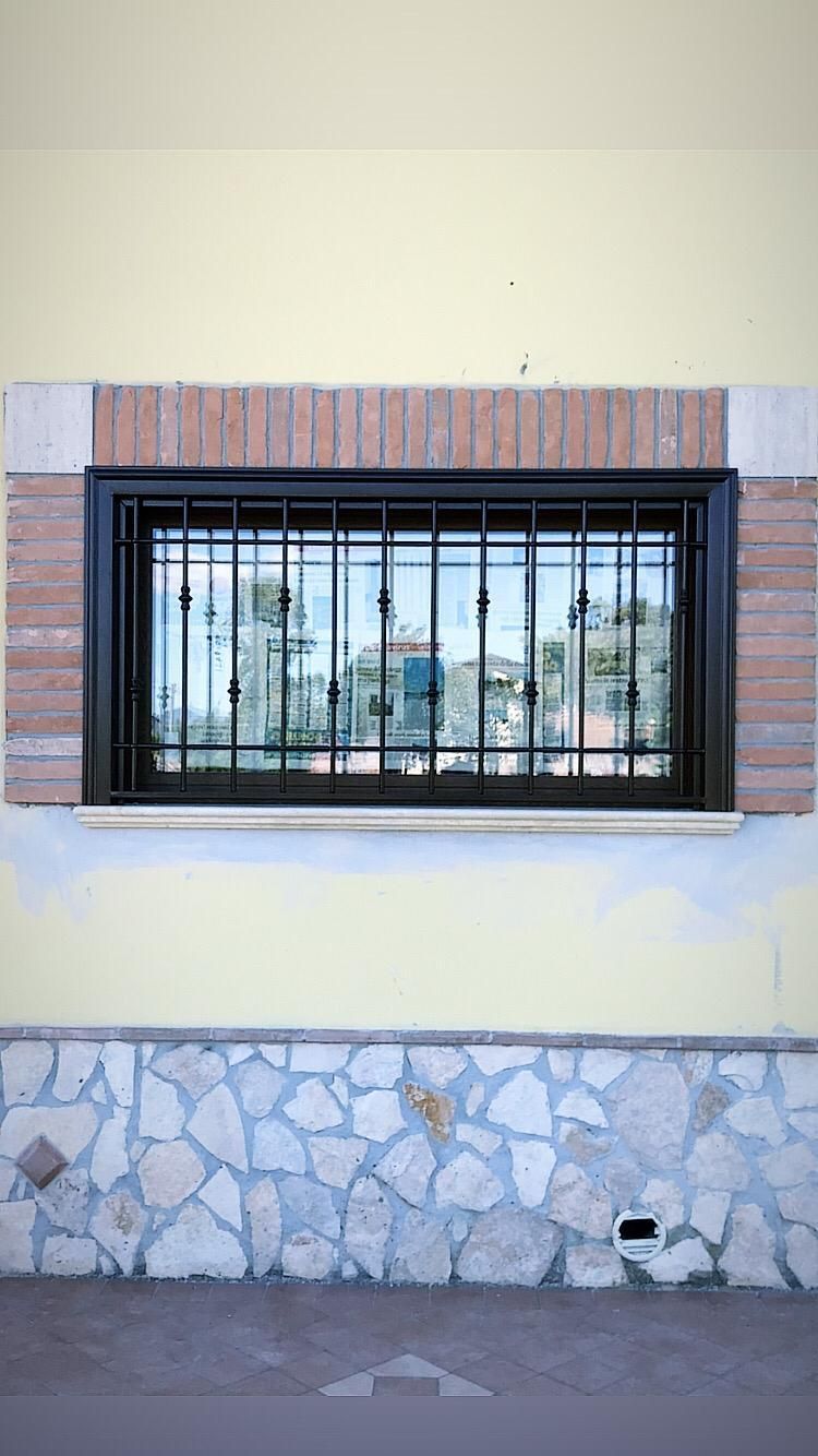 Una finestra con una griglia metallica si trova sul lato di un edificio.