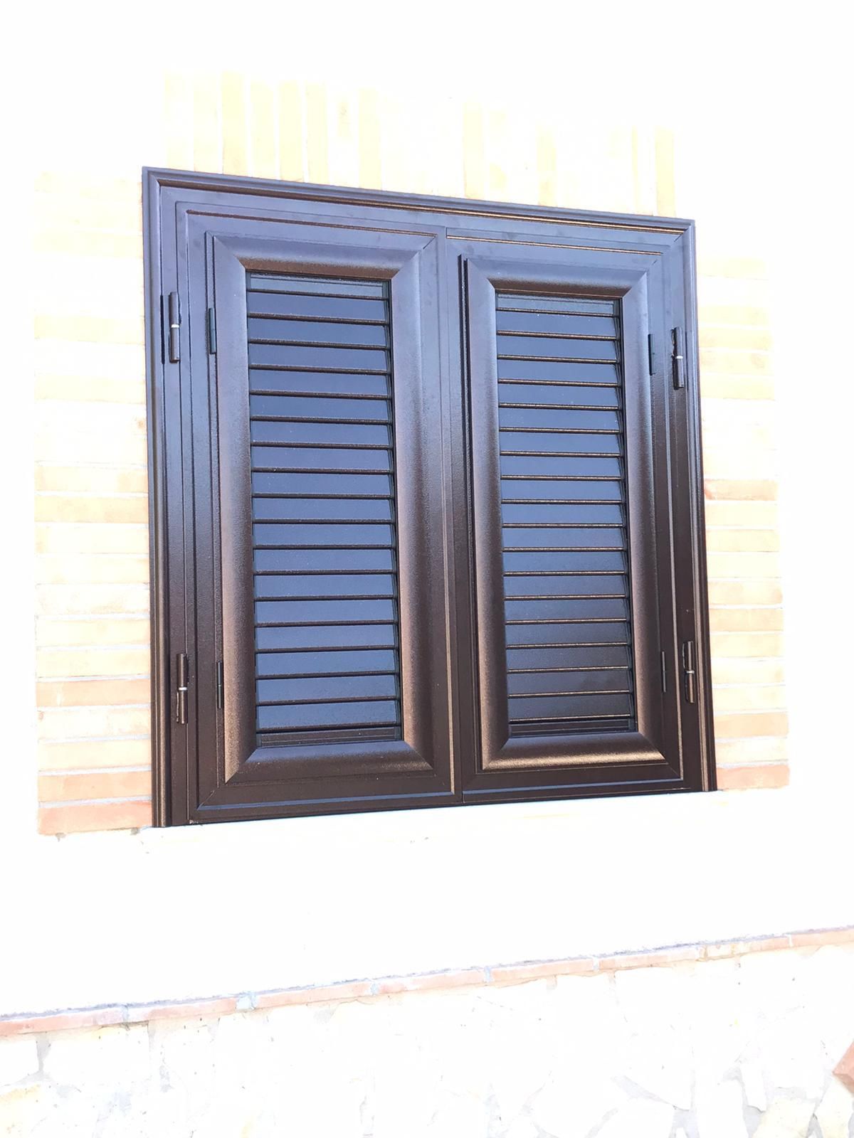 Una finestra con le persiane si trova su un muro di mattoni.