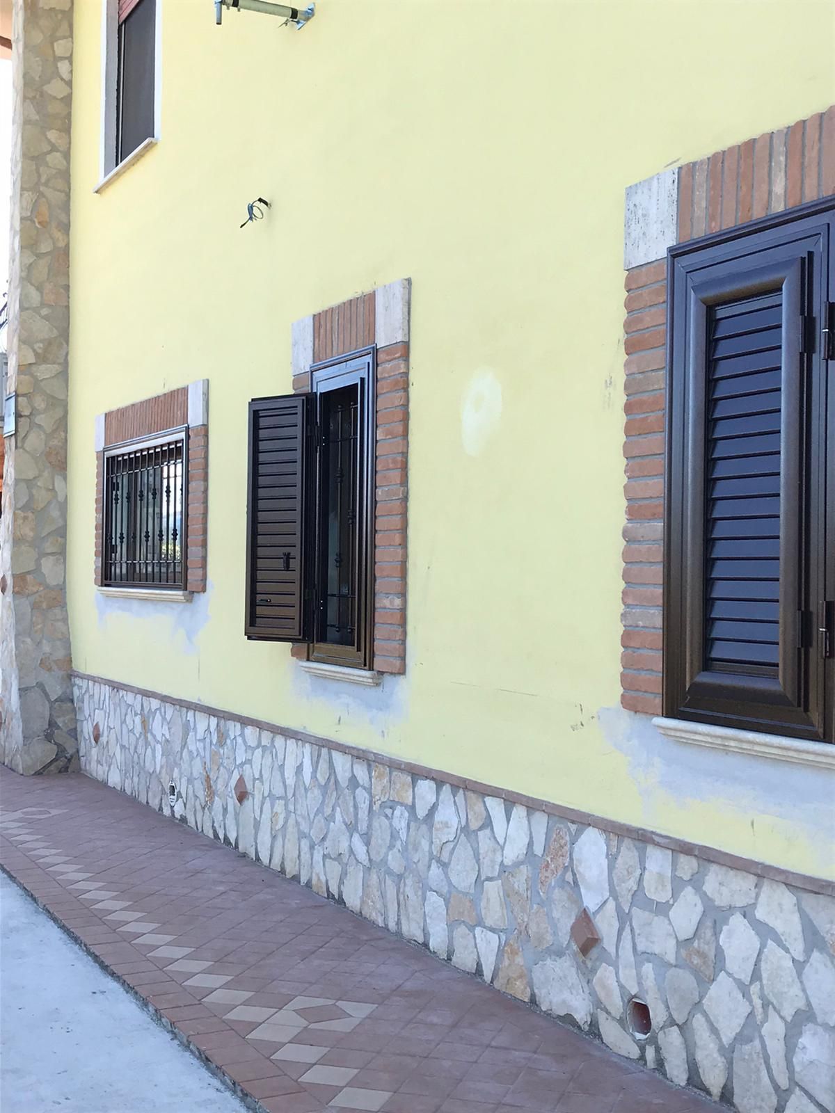 Un edificio giallo con persiane marroni alle finestre